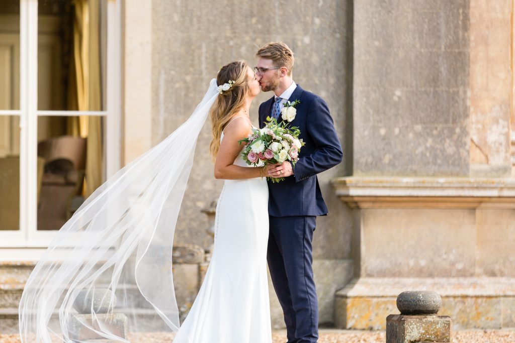 Bride and groom sharing a kiss on the steps at Turvey House, Bedfordshire, captured by Sarah Oliver of SO Studios Wedding Photography.