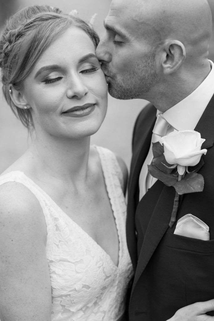 Groom kissing bride. Photography by So Studios, Essex