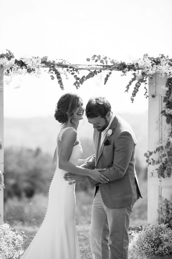 Bride and groom laughing and celebrating after their wedding at a 17th-century villa in the Tuscany hills, near Volterra, Italy.