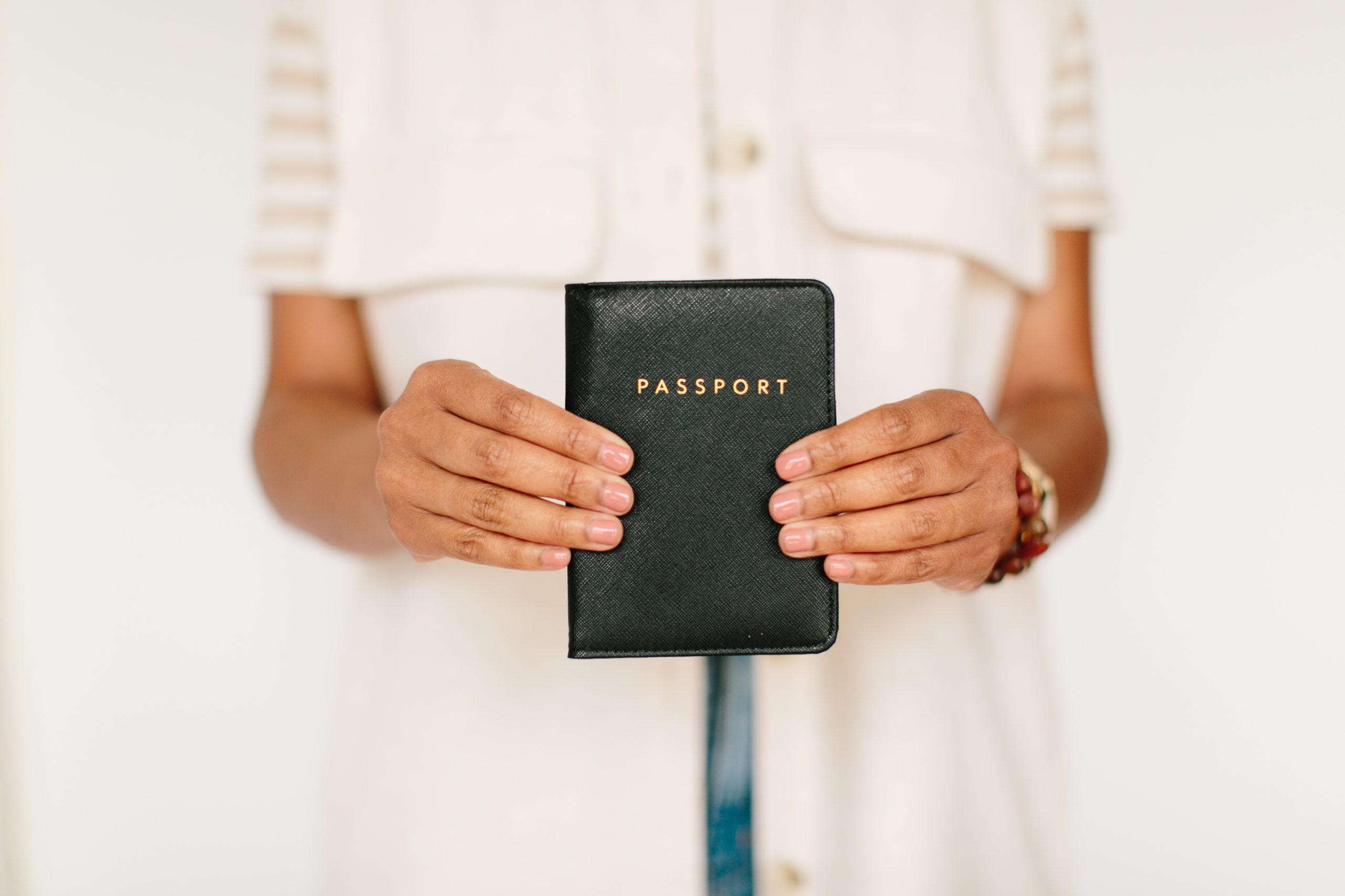 A woman holding a passport in a black leather cover with the word 